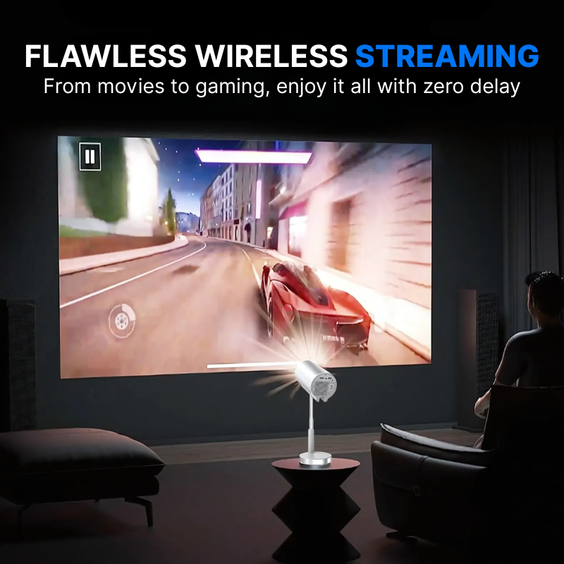 A silver portable projector illuminates a large screen in a dim living room, projecting a vibrant racing game featuring a red sports car speeding through a city at night, as a person relaxes in a brown armchair, with promotional text 'FLAWLESS WIRELESS STREAMING' above