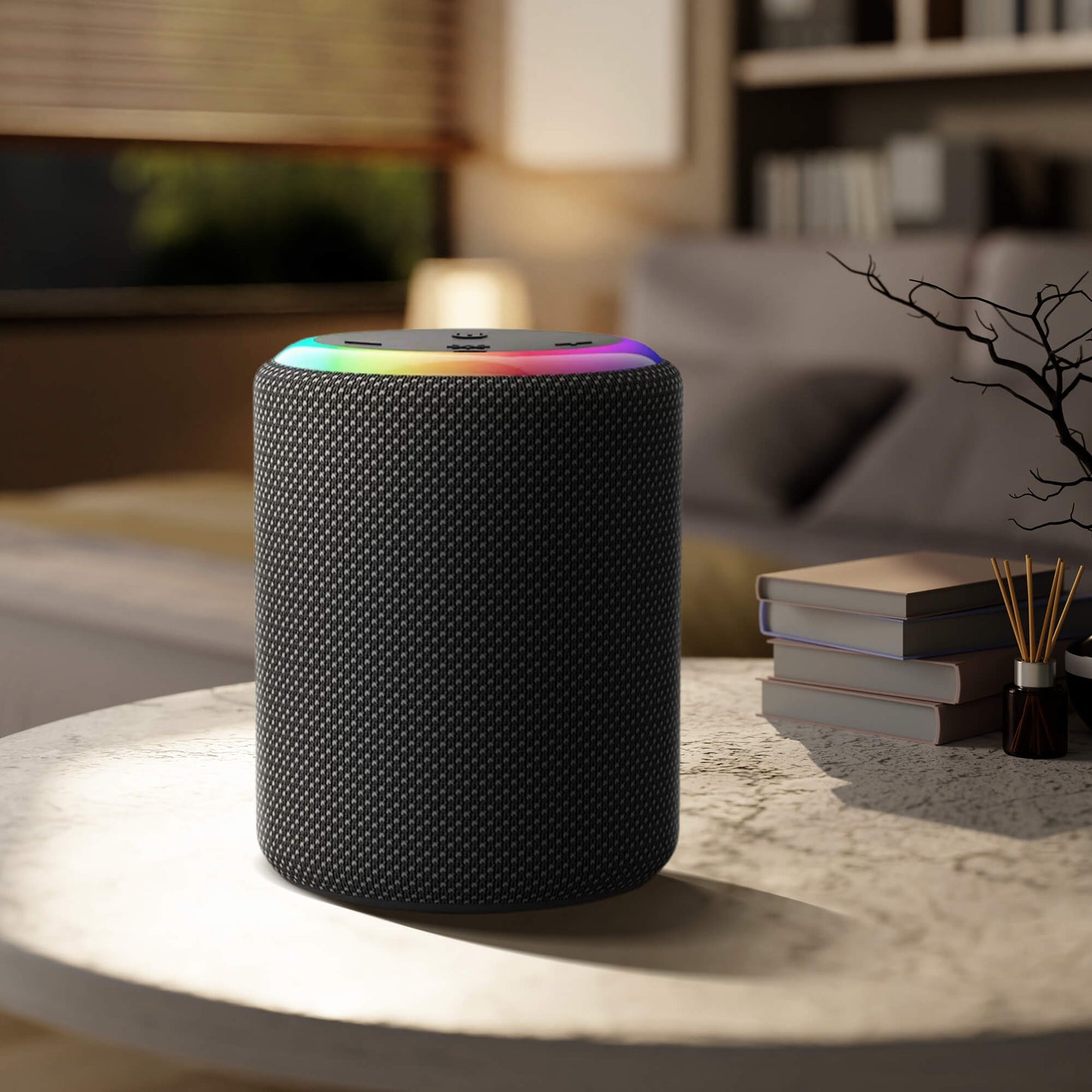 A black cylindrical smart speaker with a glowing rainbow LED ring rests on a light coffee table in a modern living room, beside a stack of books and a reed diffuser