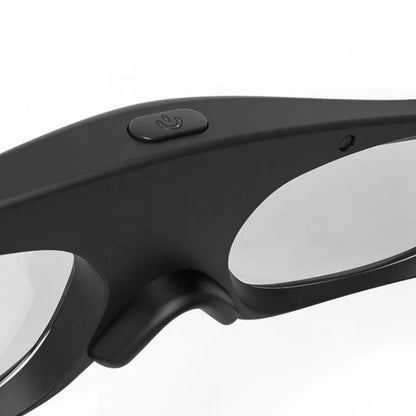 Close-up of black smart glasses with a matte finish, showcasing a power symbol button on the top frame and reflective grey lenses against a plain white background