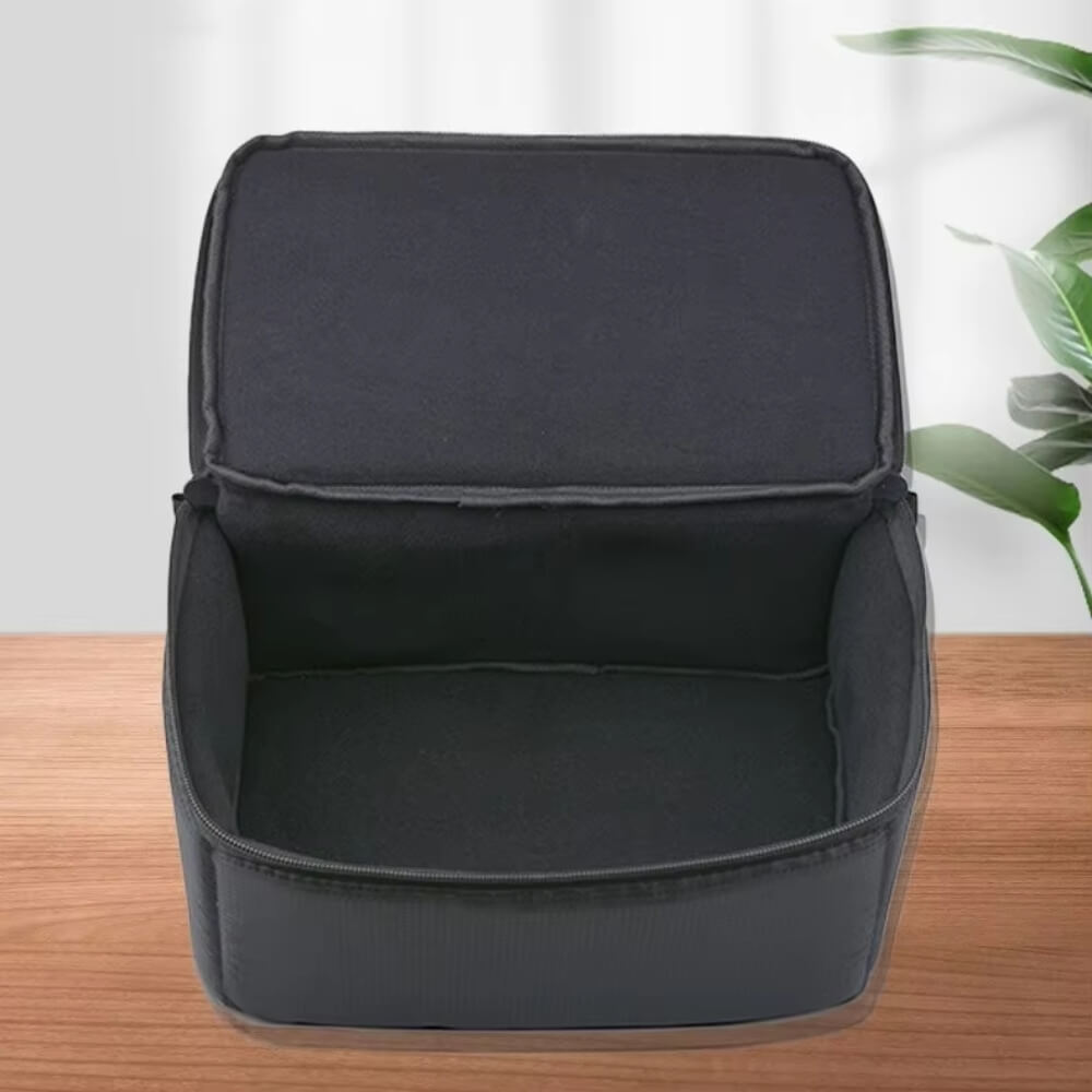 Open dark grey protective carrying case with a soft fabric interior lining and visible zipper detail sitting on a wooden table with a green plant accent