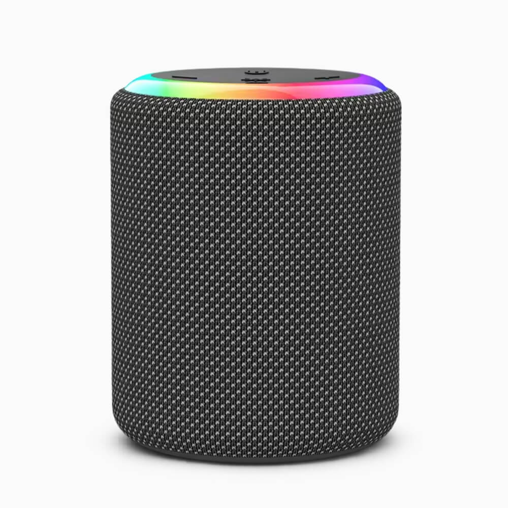 Product Photography a cylindrical portable speaker on a white background featuring a dark grey woven fabric grille a vibrant rainbow LED light ring and subtle control buttons on its top surface